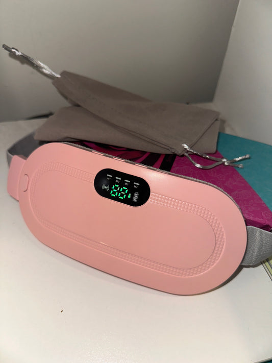 A sleek pink electronic device featuring a digital display, placed on a clean white surface beside a soft gray drawstring pouch and subtle background accents.